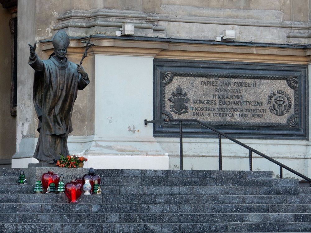 La statua di Giovanni Paolo II nella chiesa Kościół Wszystkich Świętych e la dedica della chiesa sulla pietra