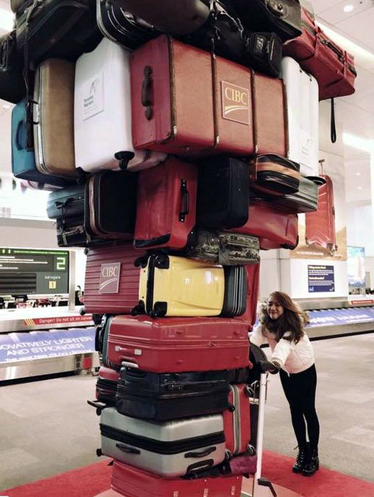 Meme di una signora con tanti bagagli a mano su un carrello