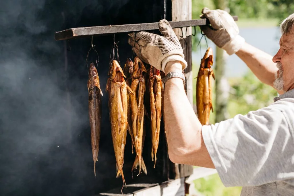 Uomo che appende dei pesci ad affumicare: cucina finlandese